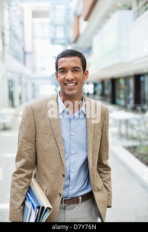 Businessman smiling on city street Stock Photo