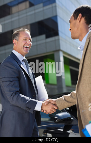Businessmen shaking hands outdoors Stock Photo