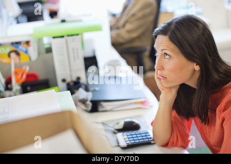 Businesswoman resting chin in hand on desk Stock Photo