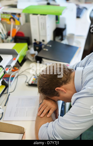 Businessman resting head on desk Stock Photo