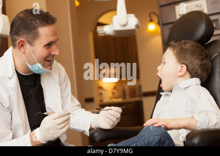Caucasian dentist examining boy's teeth in office