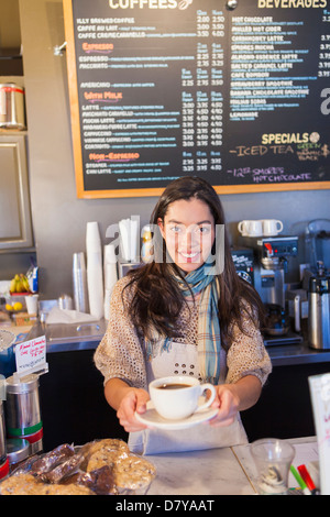 Mixed race woman working in coffee shop Stock Photo