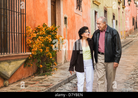 Older Hispanic couple walking on village street Stock Photo