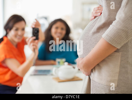 Woman taking picture of pregnant friend’s belly Stock Photo