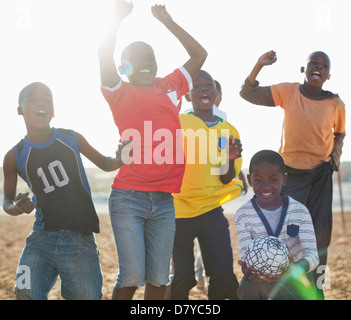 Boys playing soccer together in dirt field Stock Photo