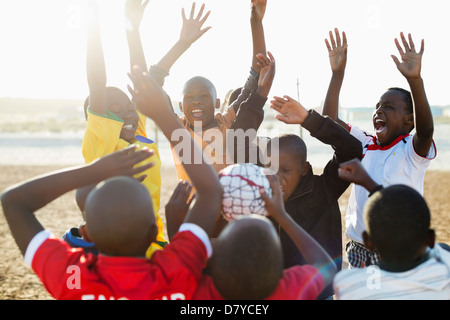 Boys cheering together in dirt field Stock Photo