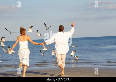 Caucasian couple running on beach Stock Photo