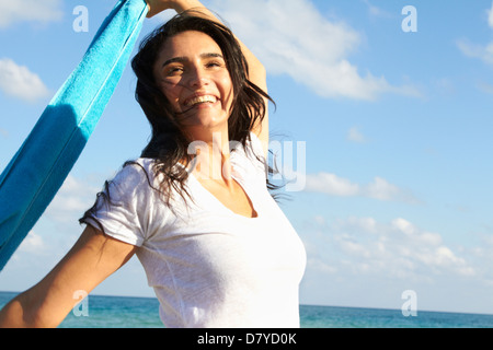 Hispanic woman playing with towel on beach Stock Photo
