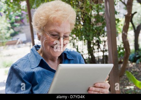 Older Hispanic woman using tablet computer outdoors Stock Photo