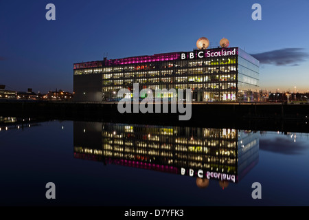 The illuminated BBC Scotland Headquarters on Pacific Quay reflected in the River Clyde at sunset, Glasgow, Scotland, UK Stock Photo