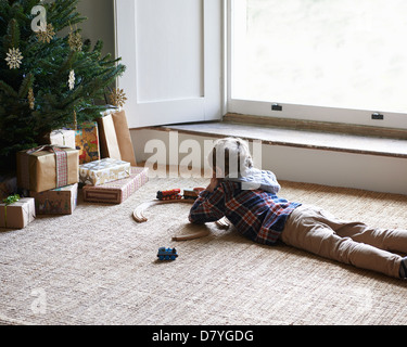 Boy playing with trains by Christmas tree Stock Photo