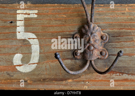 Rusty coat hook hanger with bizarre male figure on wooden vintage clothes rack. Stock Photo