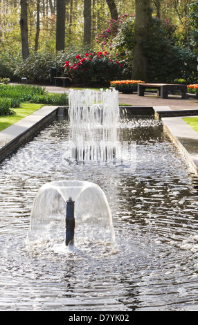 Park with springflowers and fountains spraying water in pond Stock Photo