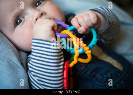 A baby boy playing with teething rings. Stock Photo