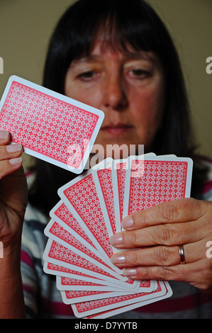 Woman choosing a card to play out of hand, England, UK, Western Europe. Stock Photo
