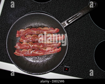 Bacon frying in pan on stove top Stock Photo