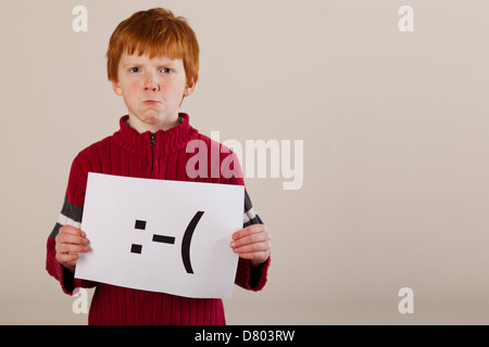 Caucasian boy holding card with sad face Stock Photo