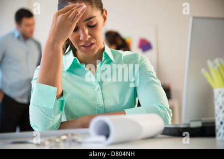 Businesswoman rubbing her forehead at desk Stock Photo