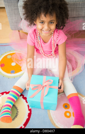 African American girl opening present in living room Stock Photo