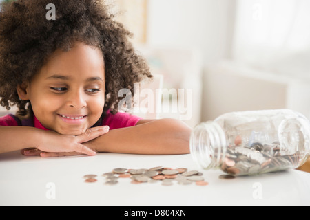 African American girl counting change in jar Stock Photo