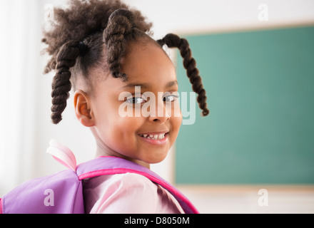 side view of smiling african american student in eyeglasses typing on ...