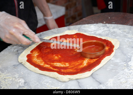 man making pizza spreading tomato sauce over the base deliberate motion blur Stock Photo
