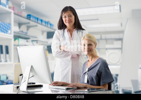 Doctor and nurse smiling at computer in hospital Stock Photo
