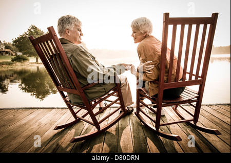 Older Caucasian couple sitting on wooden dock Stock Photo