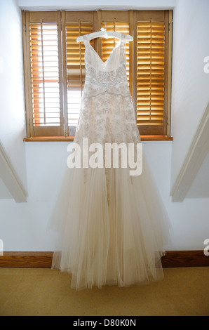 Brides wedding gown hanging up in window Stock Photo
