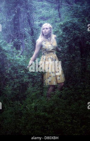 a blond girl with a yellow dress in the woods Stock Photo