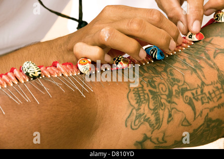 PHUKET, THAILAND OCTOBER 2 2011: A spirit medium has his arms pierced with needles at the Phuket begetarian Festival. Stock Photo