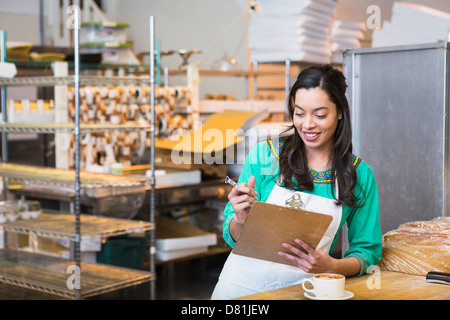 Mixed race woman working in bakery kitchen Stock Photo