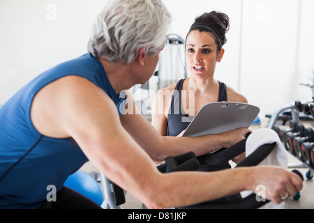 Older Hispanic man working with trainer in gym Stock Photo