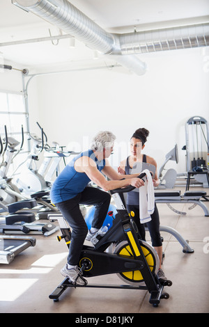 Older Hispanic man working with trainer in gym Stock Photo