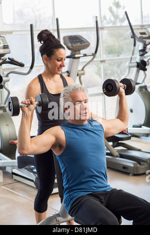 Older Hispanic man working with trainer in gym Stock Photo