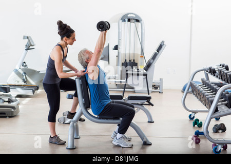 Older Hispanic man working with trainer in gym Stock Photo