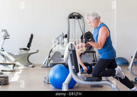 Older Hispanic man lifting weights in gym Stock Photo