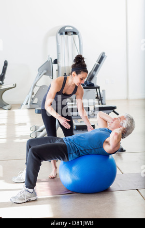 Older Hispanic man working with trainer in gym Stock Photo