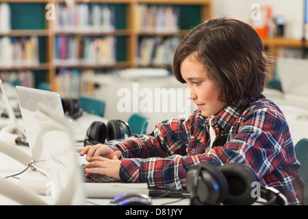 Caucasian boy using laptop in library Stock Photo