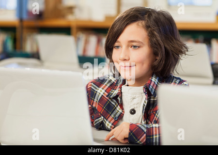 Caucasian boy using laptop in library Stock Photo