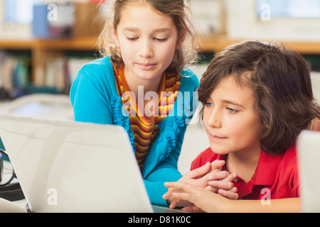 Caucasian children using laptop in library Stock Photo