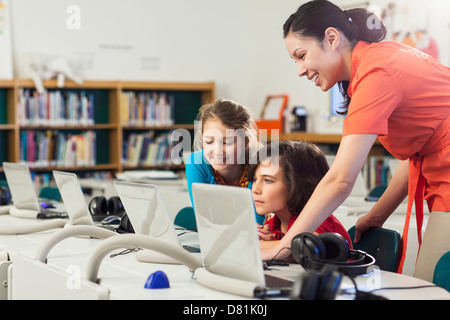 Teacher and children using laptop in library Stock Photo