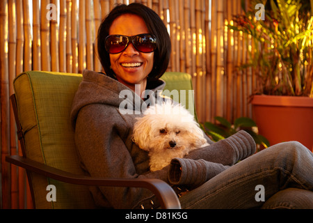 Mixed race woman sitting with dog outdoors