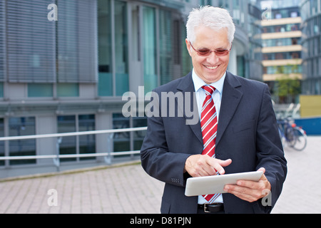 Elderly smiling business man looking at tablet PC in his hand Stock Photo