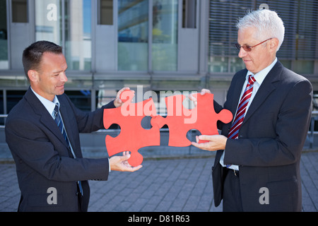 Business people solving a problem symbolized with two red jigsaw puzzle pieces Stock Photo