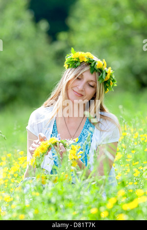 woman with flower wreath siting in a spring meadow Stock Photo