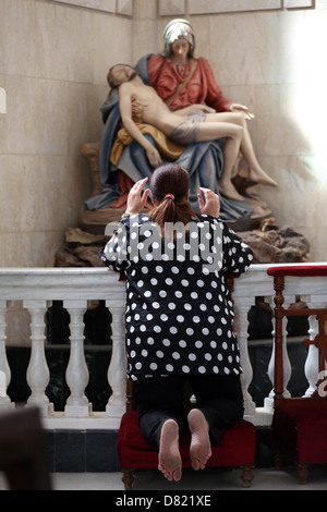 christian woman prays in front o a pieta in a catholic coptic church in Cairo Egypt Stock Photo