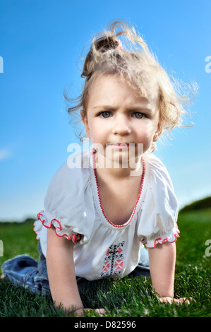 Curious baby girl crawling on the green grass in the park Stock Photo