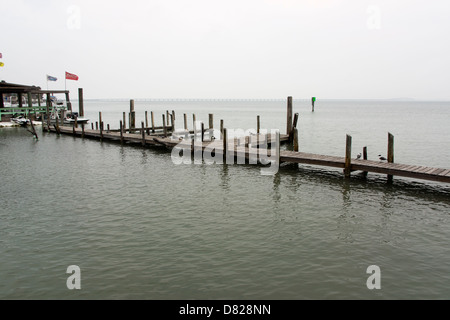 Boat docks on an overcast day in Laguna Madre at South Padre Island, Texas. Queen Isabella Bridge in the haze in the background Stock Photo