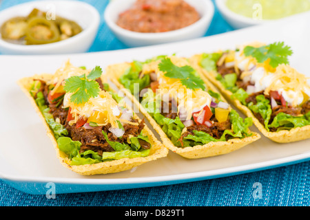 Beef Tacos - Shredded beef taco trays topped with salsa, sour cream and grated cheese. Stock Photo